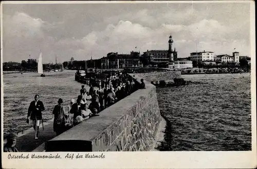 Ak Ostseebad Warnemünde Rostock, Spaziergänger auf der Westmole, Blick zum Leuchtturm und Ort