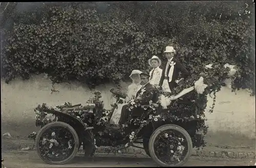 Foto Ak Hochzeitspaar in einem mit Blumen geschmückten Automobil
