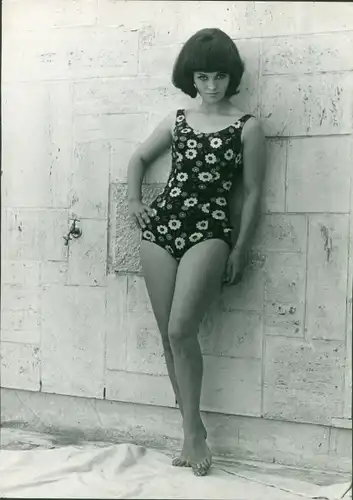 Akt Fotografie Lilo Korenjak, Frau in geblümtem Badeanzug, stehend an einer Wand