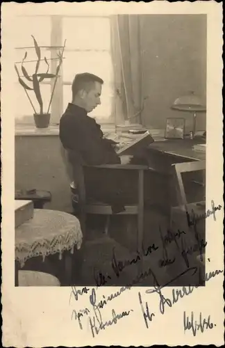 Foto Ak Mann mit Buch an einem Schreibtisch, Portrait