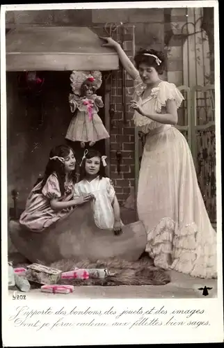 Ak Ganzkörperportrait, Mutter posiert im Kleid am Kamin mit Kindern, Geschenke, Puppe