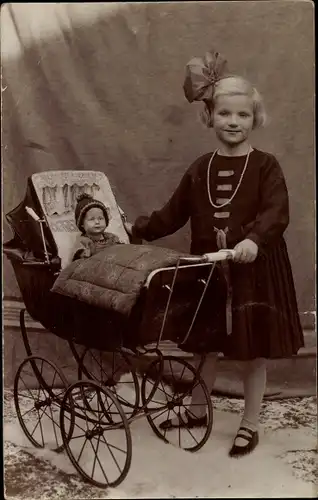 Foto Ak Mädchen im Kleid mit Schleife im Haar, Puppenwagen