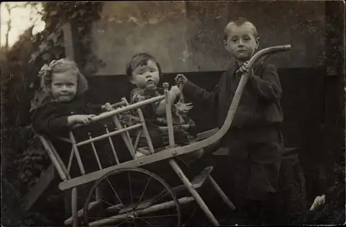 Foto Ak Drei kleine Kinder mit Handkarren