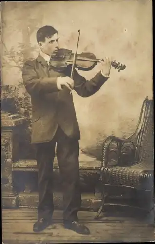 Foto Ak Junger Mann Geige spielend, Sessel
