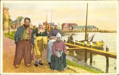 Künstler Ak Volendam Nordholland Niederlande, op de dijk, drei Frauen mit Holländerhaube u. ein Mann