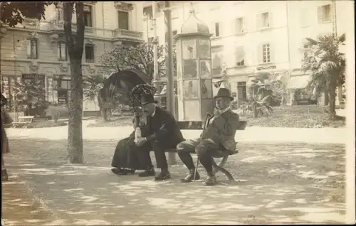Foto Ak Lugano Kanton Tessin Schweiz, Männer auf einer Bank, Dame mit Schirm, Litfaßsäule