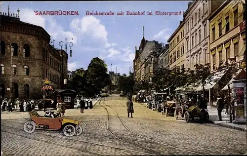 Ak Saarbrücken, Reichsstraße mit Bahnhof im Hintergrund, Schienen, Autos