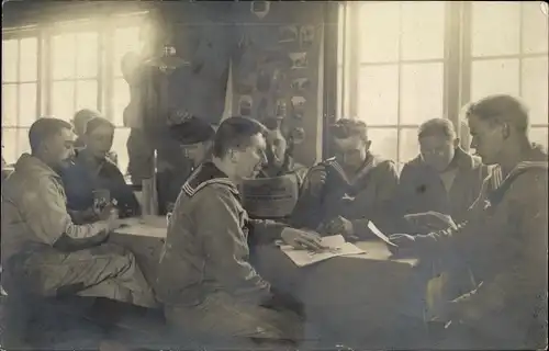 Foto Ak Deutsche Marinesoldaten in einem Heim, Kartenspiel, Nähen, Briefe, Soldatenleben, 1917