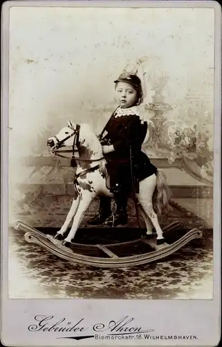Foto Kinderportrait, Kleiner Junge auf einem Schaukelpferd