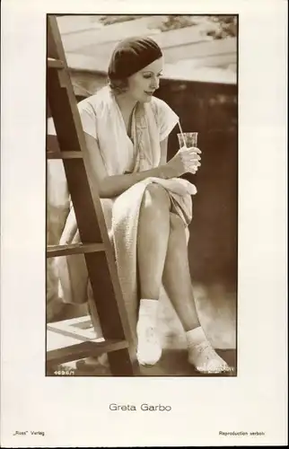 Ak Schauspielerin Greta Garbo, Portrait, sitzend, Mütze, Trinkglas