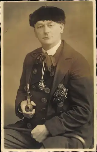 Foto Ak Portrait eines Mannes mit Pfeife, Abzeichen, Pelzmütze