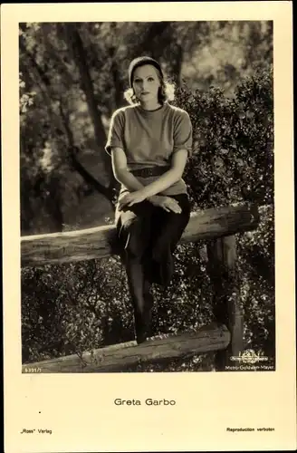 Ak Schauspielerin Greta Garbo, Portrait sitzend auf Holzzaun