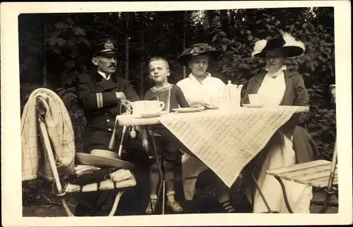 Foto Ak Kaiserlicher Marine Offizier mit Frauen und Junge an einem Tisch, Uniform