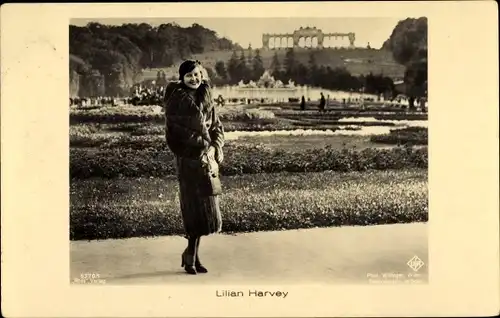Ak Schauspielerin Lilian Harvey, Standportrait, Gartenanlagen