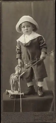 Foto Kinderportrait, Kleinkind mit Spielzeugpferd auf Rollen, Peitsche