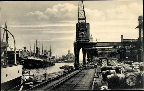 Ak Hamburg, Hafenpartie, Ladebühne mit Stückgüter, Kran, Fässer, Schienen