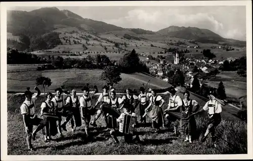 Ak Nesselwang im Allgäu, Alpspitzler, Musikgruppe in Tracht, Ort im Hintergrund