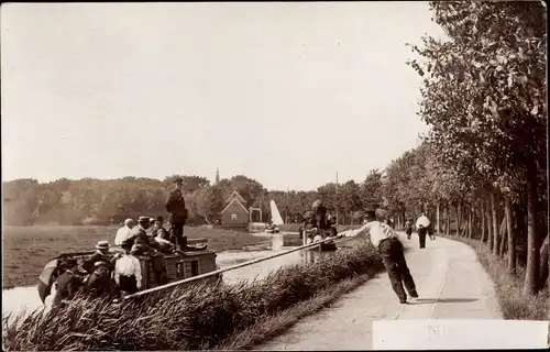 Foto Ak Niederlande, Boot auf einem Kanal, Treidelweg, Mann mit Holzstab am Ufer