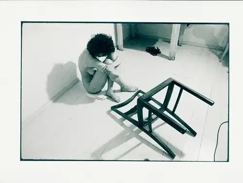 Foto Erotik, nackte Frau auf dem Boden sitzend, umgestürzter Stuhl ohne Sitzfläche