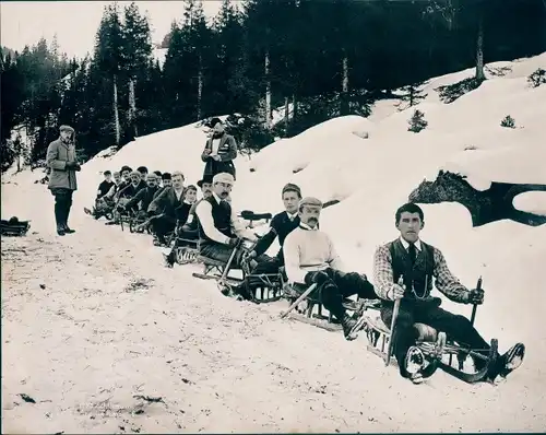 Foto Schweiz?, Männer auf Schlitten an einem bewaldeten Hang, Rodelstrecke