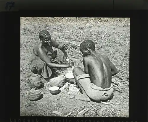 Glas Positiv Deutsch Ostafrika um 1913, Askarifrau mit ihrem Sohn beim Maismehlbrei kochen