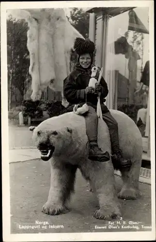 Ak Kind in norwegischen Trachten auf einem Eisbären reitend