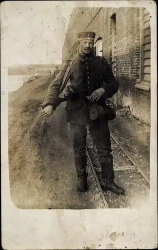 Foto Ak Deutscher Soldat in Uniform, Standportrait, Bahnschienen