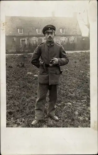 Foto Ak Deutscher Soldat in Uniform, Kaiserzeit, Im Hintergrund ein Haus, Zigarette