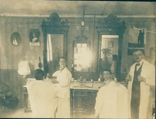 Foto Friseursalon, Friseur mit Lehrling, Kunden in Umhängen