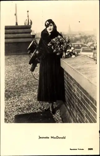 Ak Schauspielerin Jeanette MacDonald, Portrait auf dem Dach mit Blumenstrauss