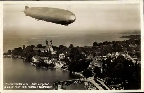 Ak Friedrichshafen am Bodensee, Luftschiff LZ 127 Graf Zeppelin über der Stadt, Fliegeraufnahme