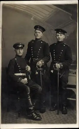 Foto Ak Deutsche Soldaten im Atelier stehend, Schirmmütze, Säbel