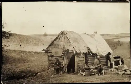 Foto Ak Unbekannter Ort, Zwei Männer vor einer Holzhütte, Osteuropa