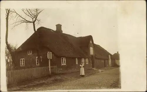 Foto Ak Christian Albrechts Koog Galmsbüll in Nordfriesland, Frau vor einem Haus mit Reetdach