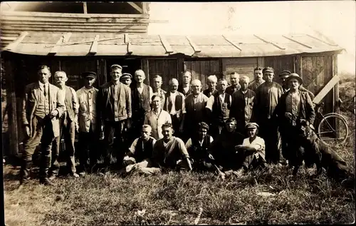 Foto Ak Männer vor einer Holzhütte, Gruppenaufnahme