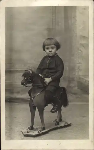 Foto Ak Kinderportrait, Kleinkind auf einem Spielzeugpferd auf Rollen