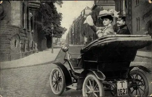 Ak Liebespaar fährt Automobil, Stadtpartie, Frau winkt mit Taschentuch, Autokennzeichen T1627