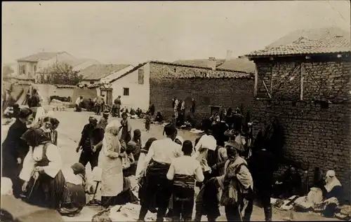 Foto Ak Unbekannter Ort, Personen in Trachten in einer Ortschaft