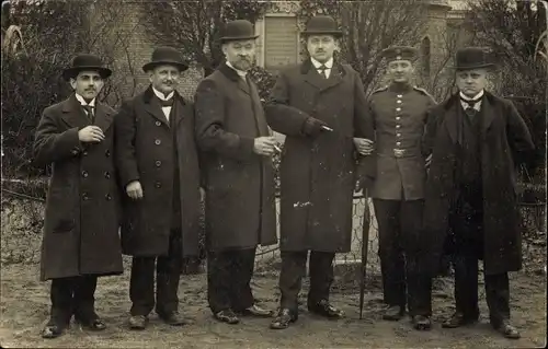 Foto Ak Männergruppe in Mänteln, Hüte, Zigaretten, Deutscher Soldat in Uniform