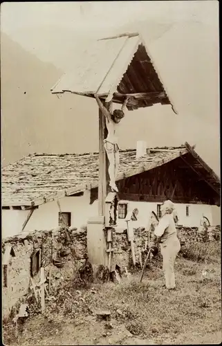 Foto Ak Mann betet an einem Kreuz, Bauernhaus