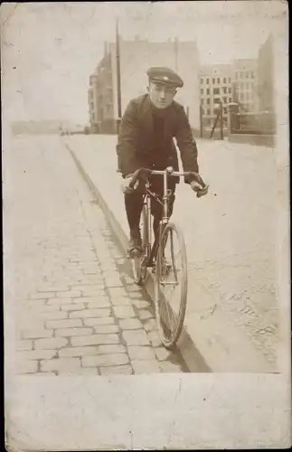 Foto Ak Junger Mann auf einem Fahrrad, Straße, Wohnhäuser