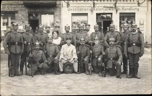 Foto Ak 1914, Soldaten, 1. WK, Kaiserreich, Gewehr, Pickelhaube, Gruppenbild, Kolonialwarenhandlung