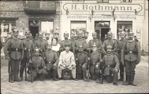 Foto Ak 1914, Soldaten, 1. WK, Kaiserreich, Gewehr, Pickelhaube, Gruppenbild, Kolonialwarenhandlung