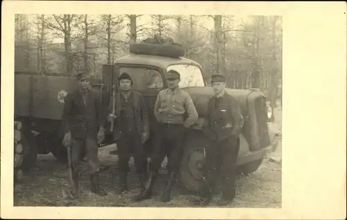 Foto Ak Vier Männer mit Äxten vor einem LKW