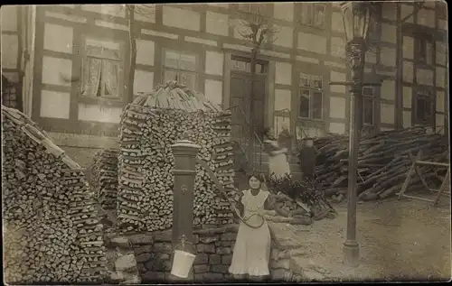 Foto Ak Lauenstein Salzhemmendorf in Niedersachsen, Frau an der Wasserpumpe, Brennholzstapel