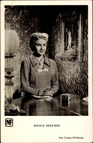 Ak Schauspielerin Nicole Heesters, Portrait an einem Tisch sitzend