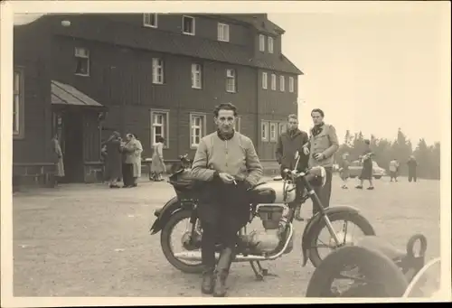 Foto Mann steht rauchend vor einem Motorrad