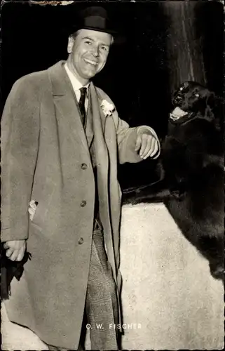 Ak Schauspieler O. W. Fischer, Ganzkörperportrait mit Hut und Mantel, schwarzer Hund