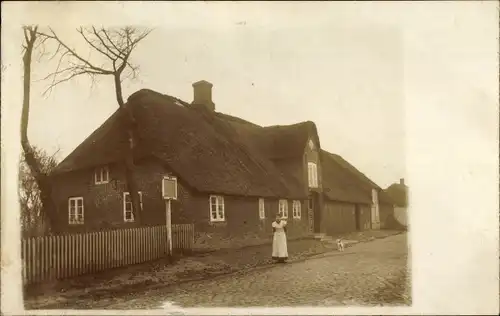 Foto Ak Christian Albrechts Koog Galmsbüll in Nordfriesland, Frau vor einem Haus mit Reetdach