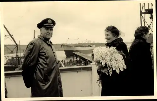 Foto Ak An Bord eines Schiffes, Frau mit Blumenstrauß, Kapitän, Frachtschiff im Hintergrund